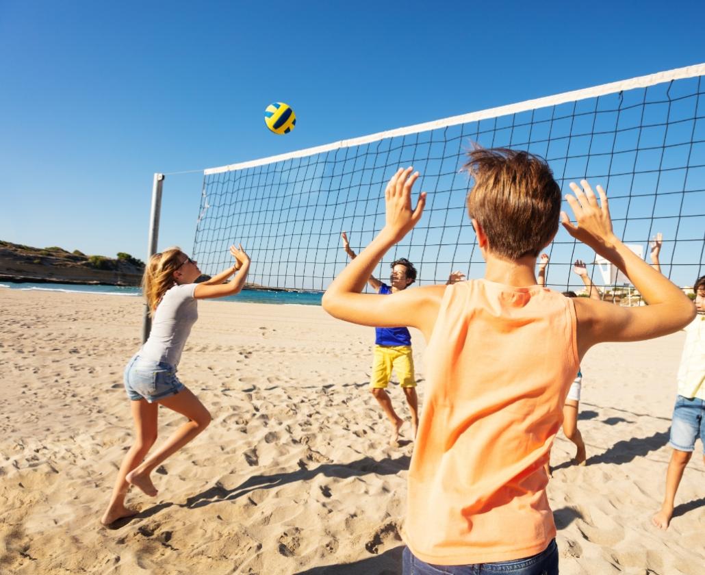 Ragazzi giocano a beach volley sulla spiaggia in una giornata di sole.