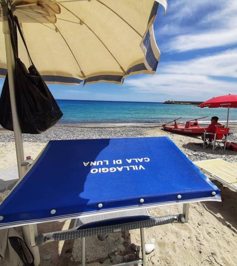 Spiaggia con ombrelloni, sdraio e mare azzurro a Cala di Luna.