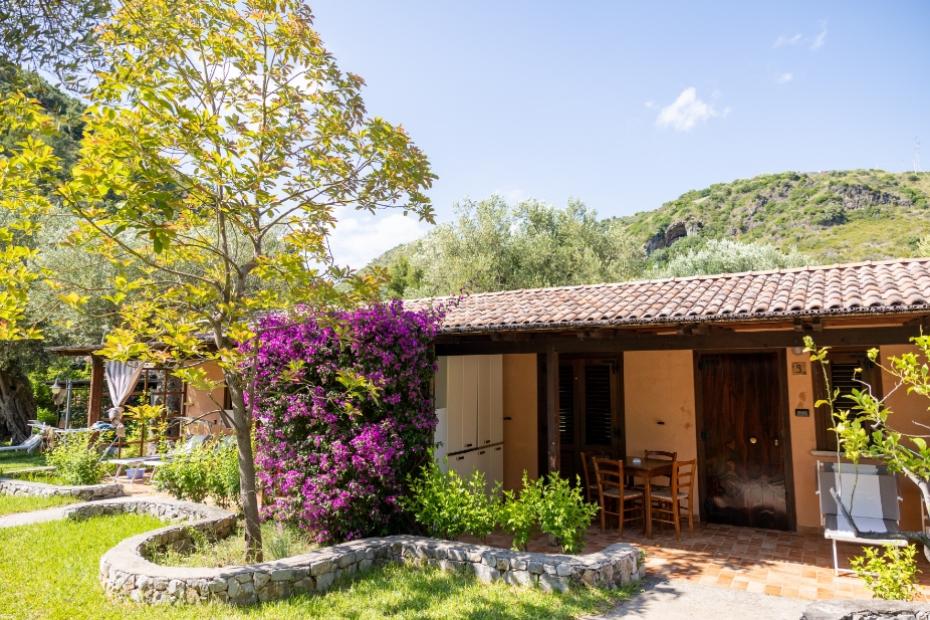 Casetta rustica con giardino fiorito, immersa nel verde collinare.